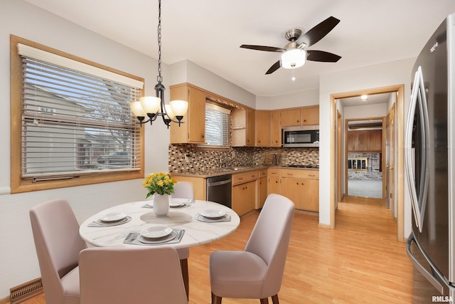 dining area with ceiling fan with notable chandelier, light wood-type flooring, and visible vents