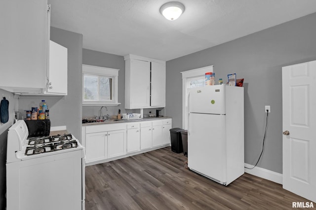 kitchen featuring white appliances, white cabinetry, a sink, and dark wood-style flooring