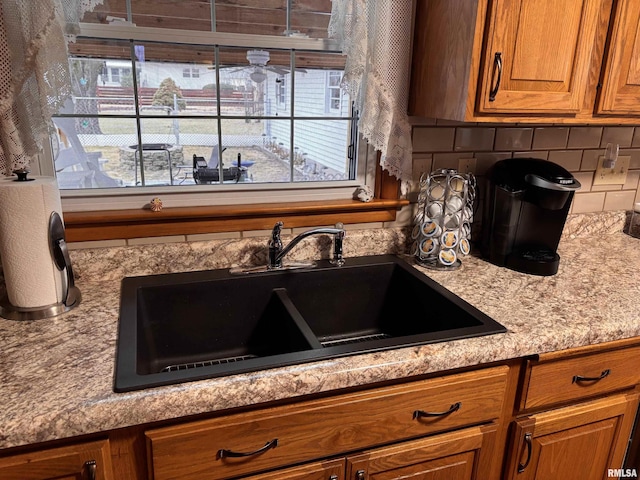 kitchen featuring brown cabinetry, a sink, and backsplash