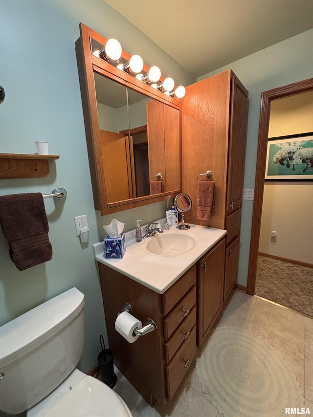 half bathroom with baseboards, vanity, and toilet