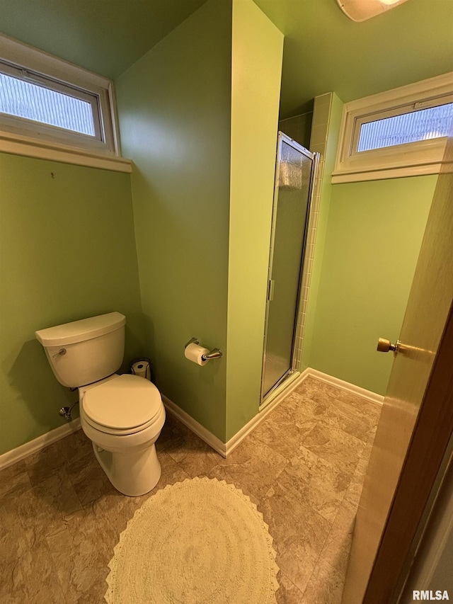 bathroom with baseboards, a shower stall, and toilet