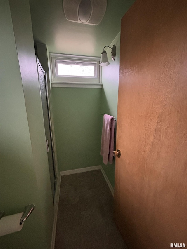 bathroom featuring a shower with door and baseboards