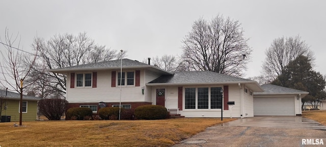 tri-level home featuring a garage, central AC unit, concrete driveway, a front lawn, and brick siding