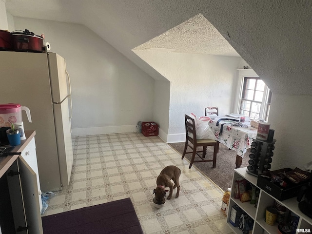 interior space with a textured ceiling, lofted ceiling, and baseboards