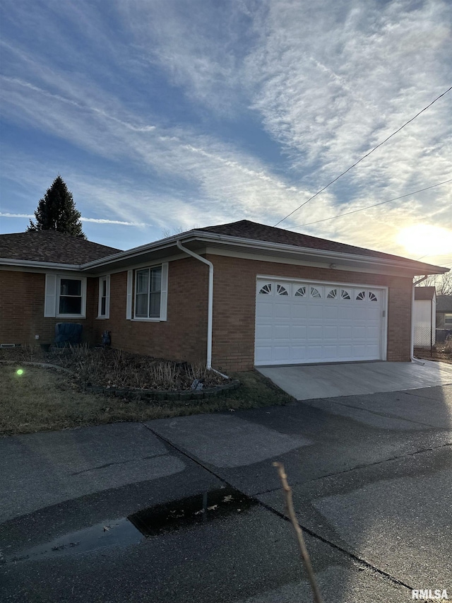 view of side of property featuring a garage, driveway, and brick siding