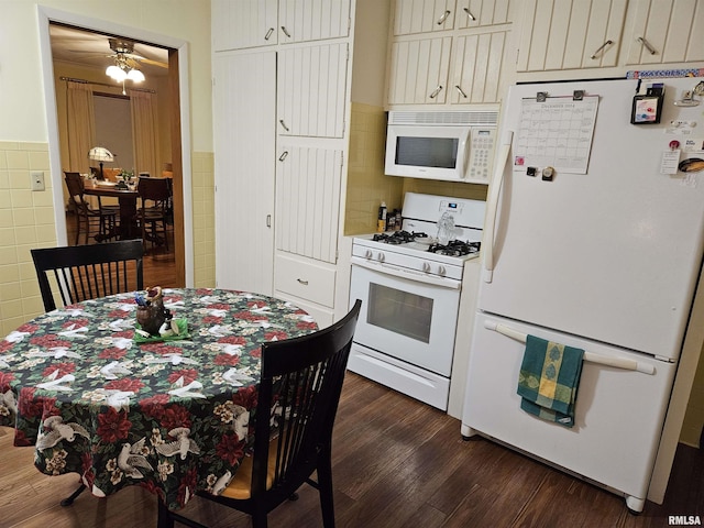 kitchen featuring white appliances, a wainscoted wall, dark wood finished floors, and tile walls