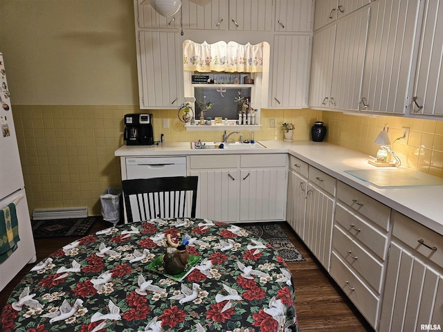 kitchen with white appliances, wainscoting, dark wood-type flooring, light countertops, and a sink