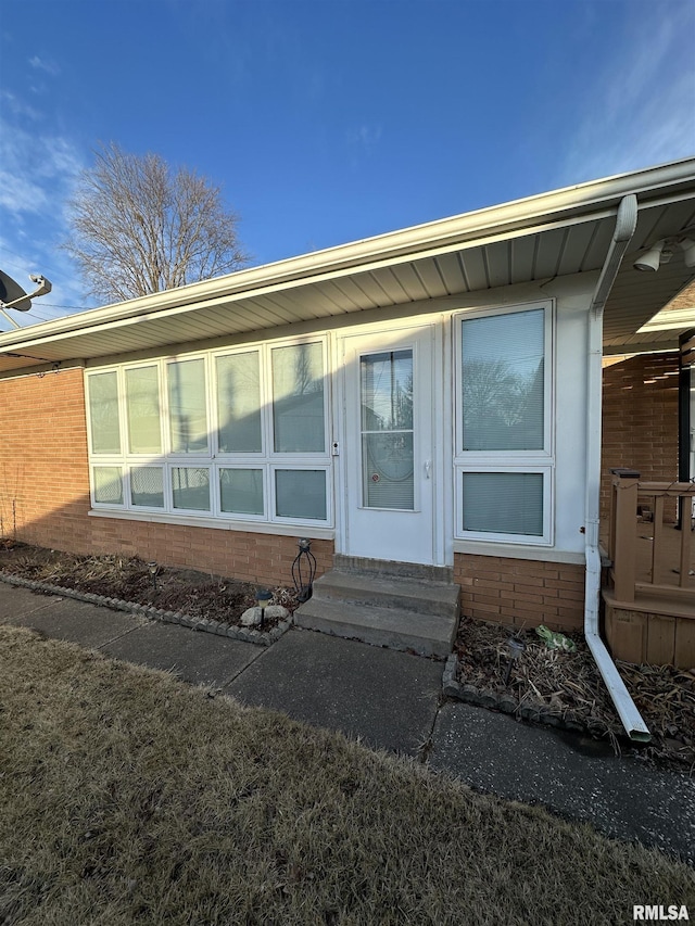 view of exterior entry featuring brick siding