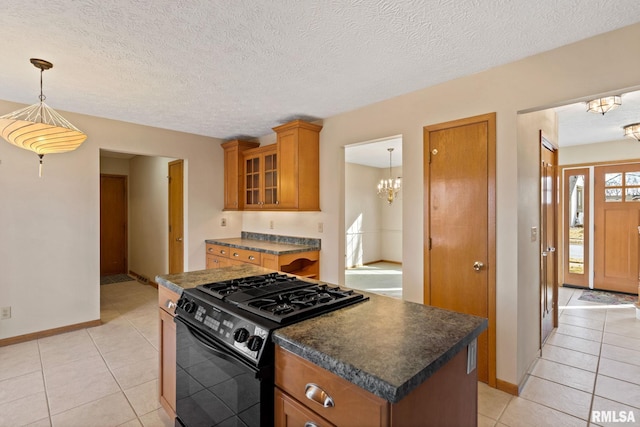 kitchen featuring a chandelier, brown cabinetry, dark countertops, and black gas stove