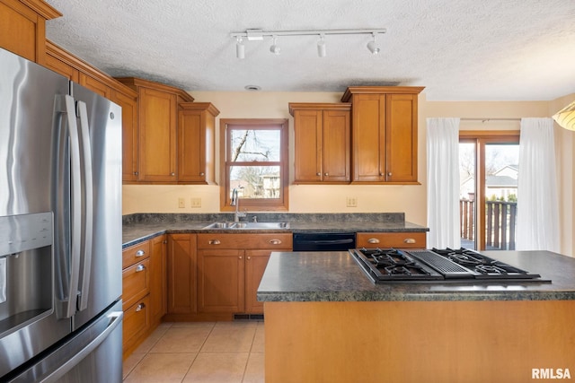 kitchen with black appliances, light tile patterned floors, brown cabinets, and a sink