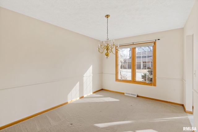 carpeted spare room featuring an inviting chandelier, baseboards, visible vents, and a textured ceiling