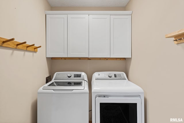 clothes washing area featuring washer and dryer, cabinet space, and a textured ceiling