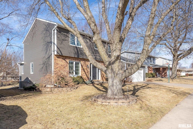 view of front of home with a front lawn, brick siding, driveway, and an attached garage