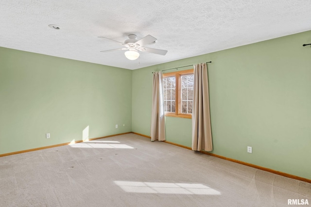 carpeted empty room featuring a textured ceiling, ceiling fan, and baseboards