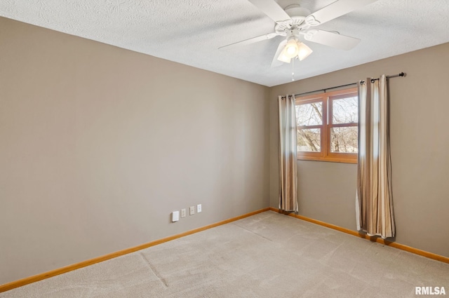 spare room featuring light carpet, a ceiling fan, baseboards, and a textured ceiling