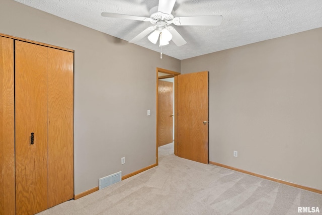 unfurnished bedroom featuring a textured ceiling, a closet, carpet flooring, and visible vents