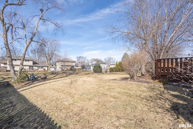 view of yard with a deck, fence, and a residential view