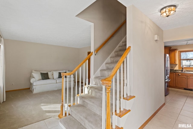 stairway with baseboards, visible vents, tile patterned floors, carpet flooring, and a textured ceiling