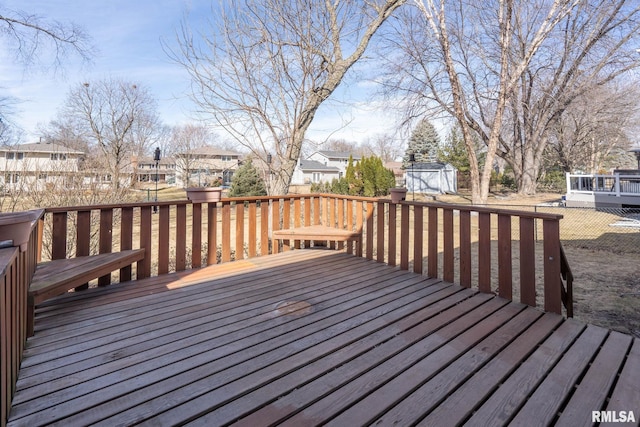 wooden deck featuring an outbuilding, a storage unit, and a residential view