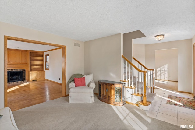 living area featuring stairs, a textured ceiling, a fireplace, and baseboards