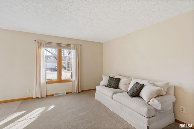 living room with baseboards, visible vents, a textured ceiling, and light colored carpet