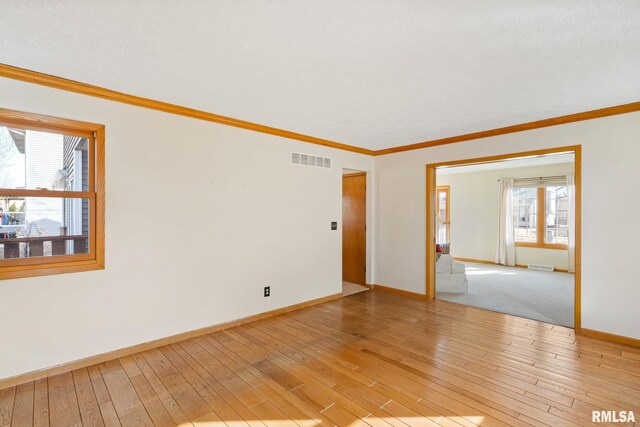 spare room featuring light wood-type flooring, visible vents, and crown molding