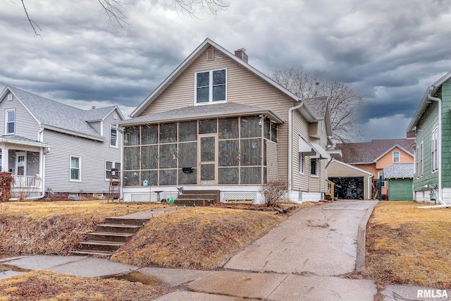 view of front of home with a chimney, a garage, and a sunroom