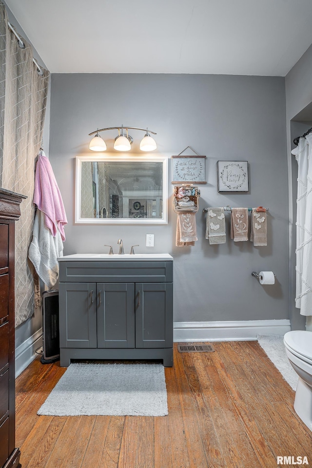 bathroom with toilet, baseboards, hardwood / wood-style floors, and vanity