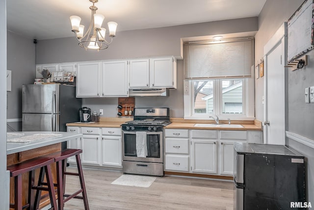 kitchen featuring a sink, white cabinets, ventilation hood, and stainless steel appliances