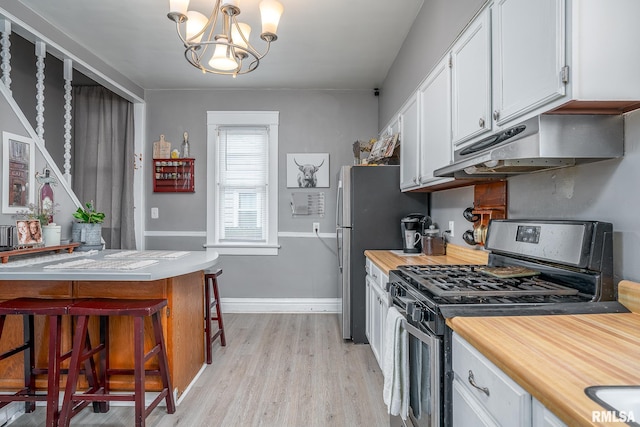 kitchen with stainless steel appliances, an inviting chandelier, white cabinets, light wood-type flooring, and under cabinet range hood