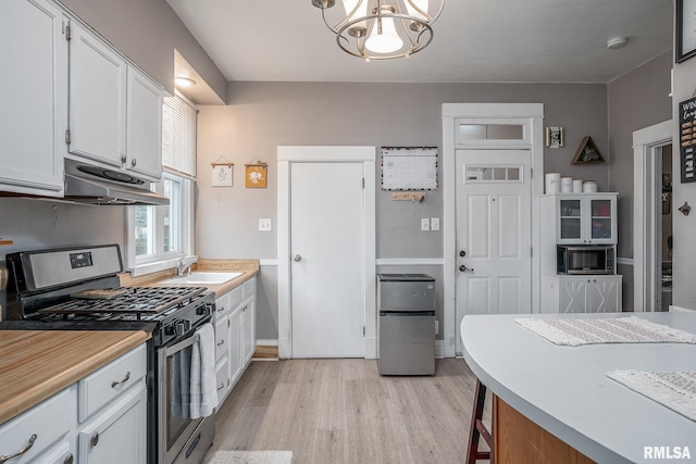 kitchen featuring white cabinets, under cabinet range hood, stainless steel appliances, and light wood-style floors