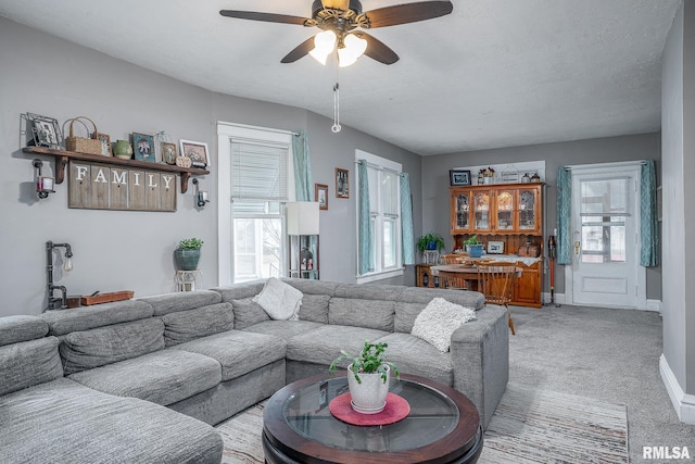 living area with light carpet, baseboards, and a ceiling fan