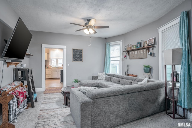 living area featuring a textured ceiling, ceiling fan, and light carpet