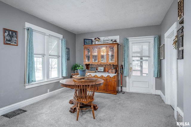 dining area featuring visible vents, light carpet, baseboards, and a textured ceiling