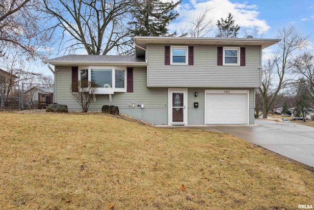 split level home featuring concrete driveway, a front lawn, and an attached garage