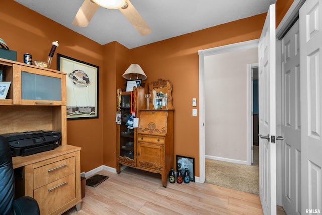 office space with a ceiling fan, light wood-type flooring, and baseboards