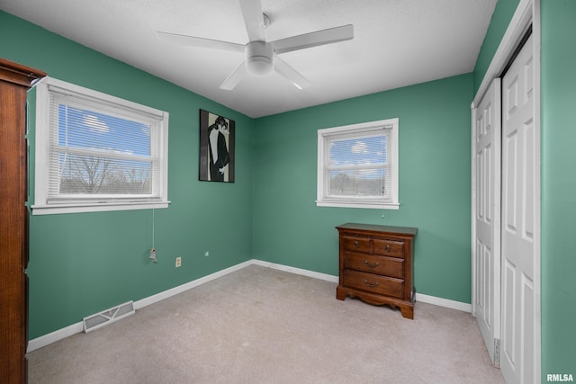 unfurnished bedroom featuring carpet, a closet, visible vents, ceiling fan, and baseboards