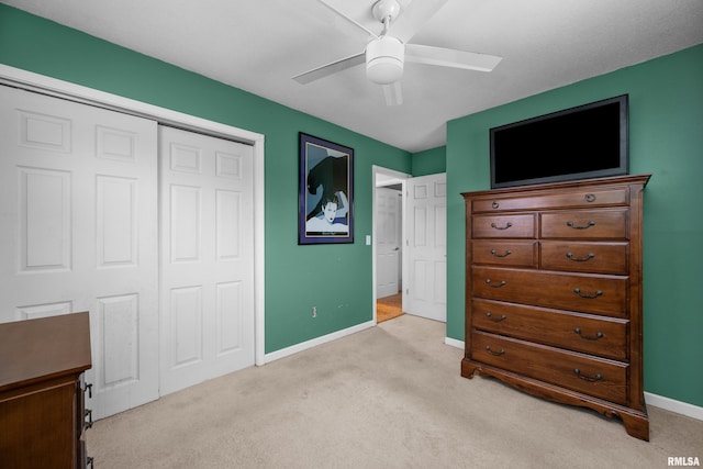 bedroom featuring light carpet, ceiling fan, baseboards, and a closet