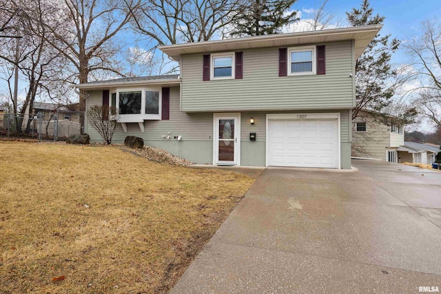 split level home with an attached garage, driveway, a front lawn, and fence