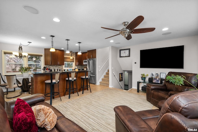 living room with ceiling fan with notable chandelier, baseboards, recessed lighting, and stairs