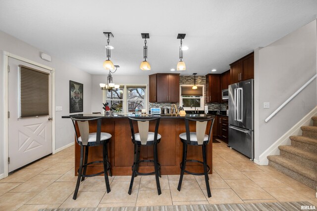 kitchen with light tile patterned floors, high end fridge, dark countertops, decorative backsplash, and a kitchen breakfast bar