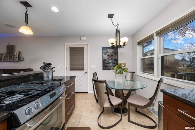 kitchen with stainless steel gas range, a chandelier, light tile patterned flooring, and hanging light fixtures