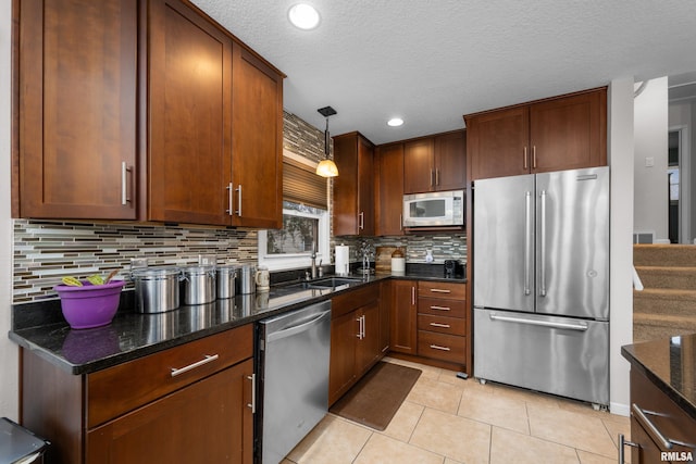 kitchen featuring dark stone countertops, stainless steel appliances, pendant lighting, backsplash, and light tile patterned flooring