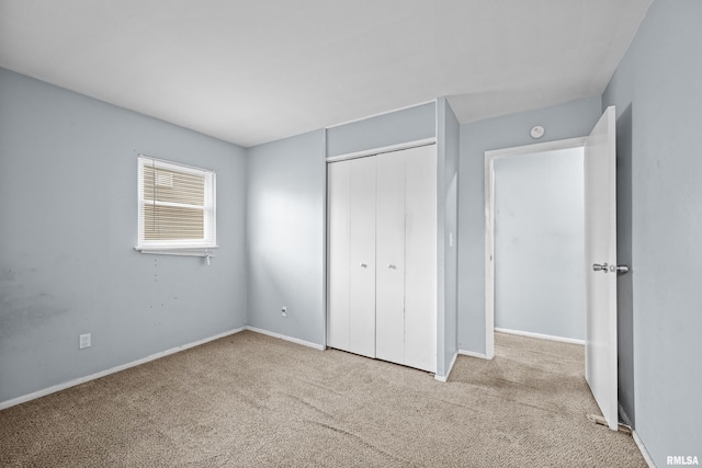 unfurnished bedroom featuring carpet floors, a closet, and baseboards