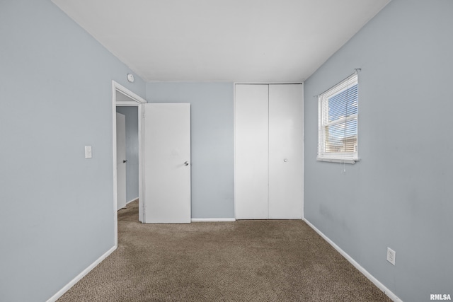 unfurnished bedroom with a closet, carpet flooring, and baseboards