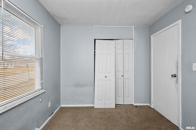 unfurnished bedroom featuring carpet floors, a closet, and baseboards