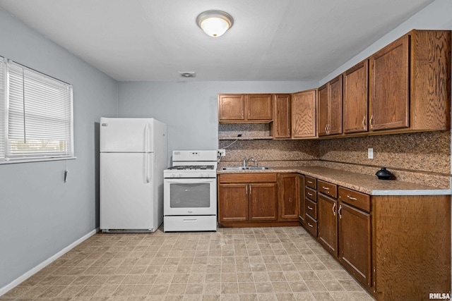 kitchen with brown cabinetry, white appliances, a sink, and backsplash