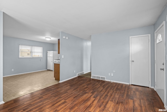 unfurnished living room featuring wood finished floors, visible vents, and baseboards