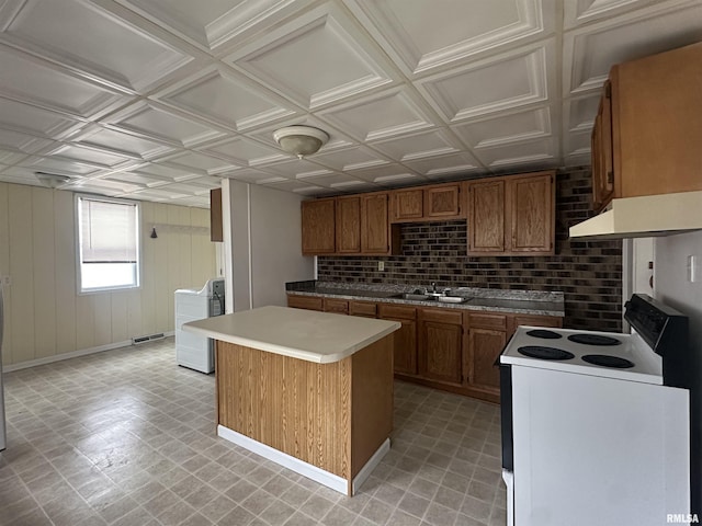 kitchen featuring an ornate ceiling, a center island, electric range, washer / dryer, and under cabinet range hood