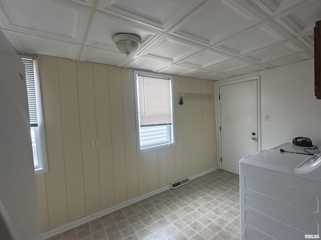 empty room with washer / clothes dryer, visible vents, wood walls, and baseboards